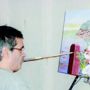 Le peintre de bouche Francisco Palos Jiménez en train de peindre un tableau avec sa bouche